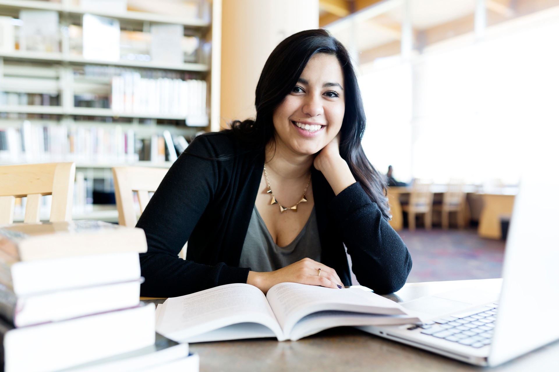 Young female college student studying with laptop in library