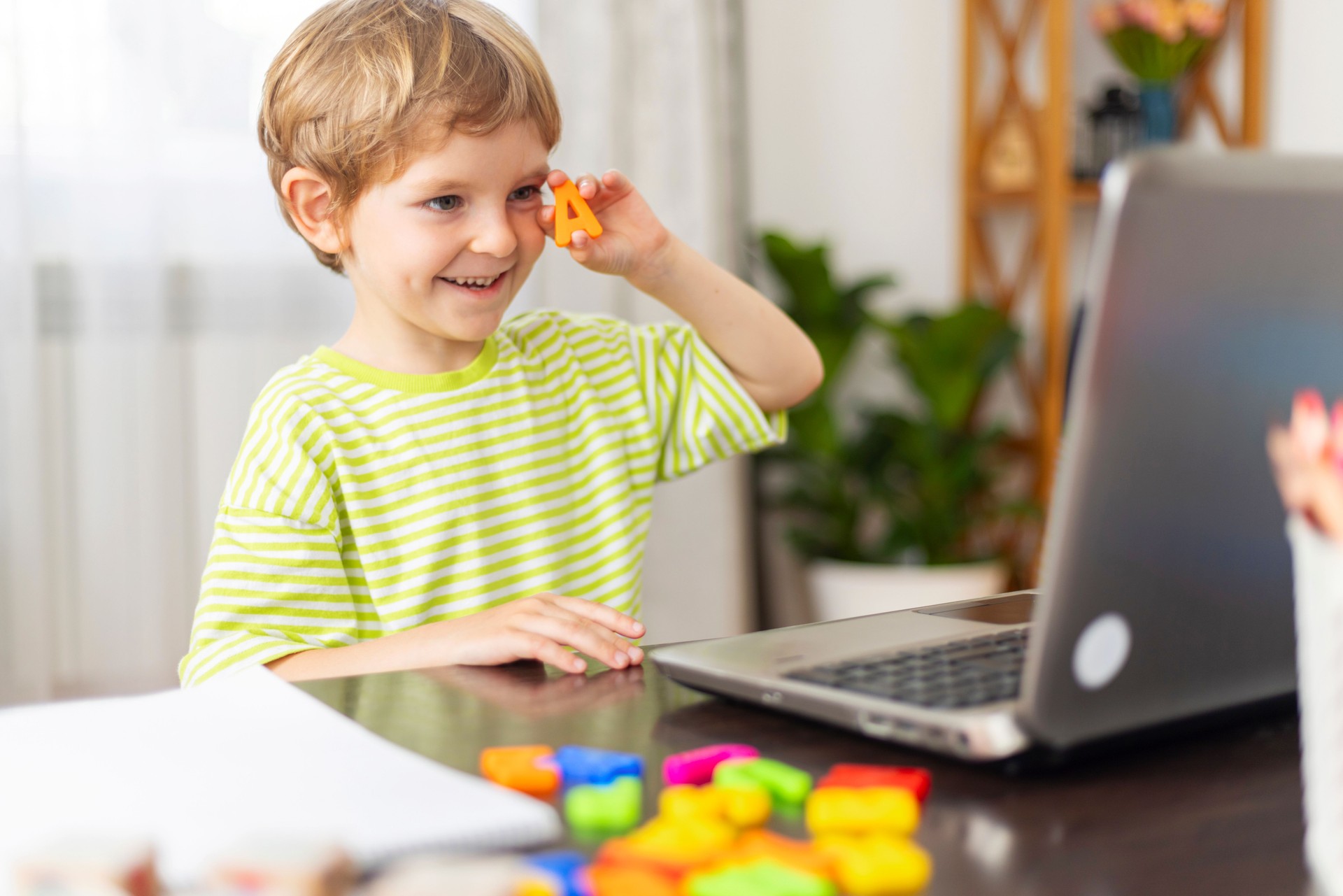 Child learning online with laptop and toys